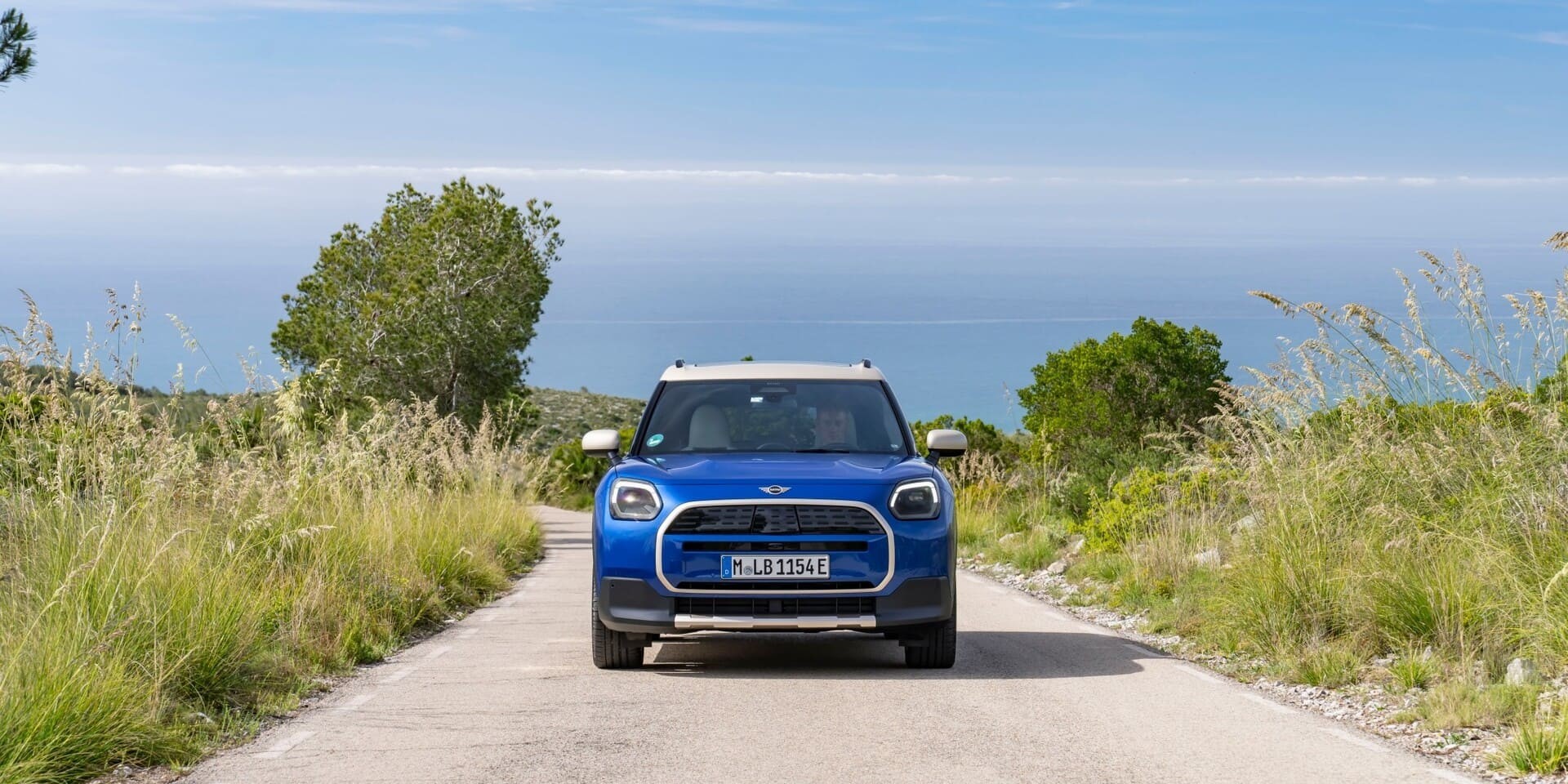 Vista frontal do MINI Countryman E a circular na estrada.